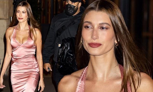 Hailey Bieber puts on a busty display in a pink silk halterneck dress