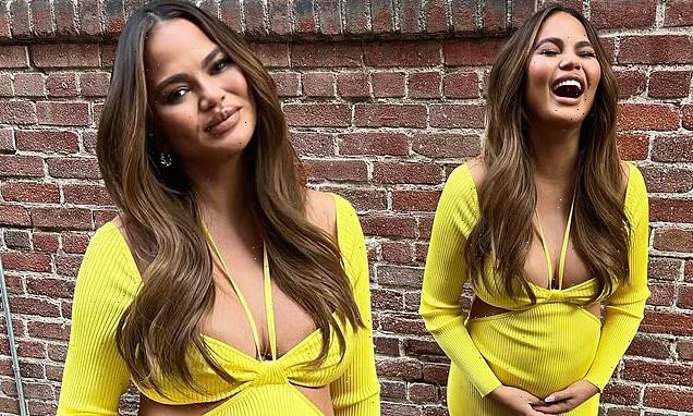 Pregnant Chrissy Teigen cradles her growing bump in a yellow dress