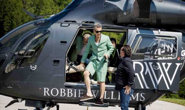 Robbie sports green co-ord as he lands in Austria in personalised chopper