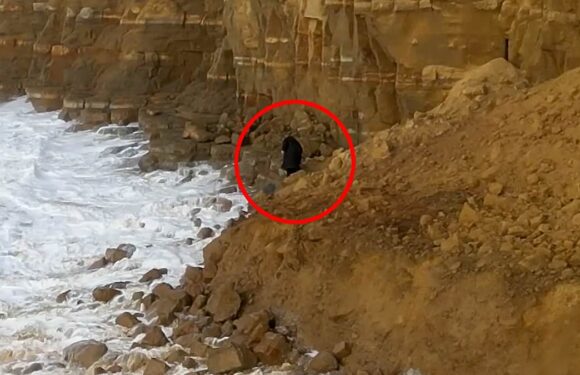 Moment mystery hooded figure risks death to climb over huge rockfall