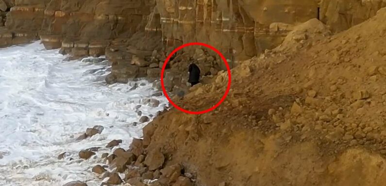 Moment mystery hooded figure risks death to climb over huge rockfall